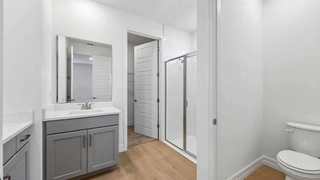 primary bathroom with two sink vanities and walk in shower