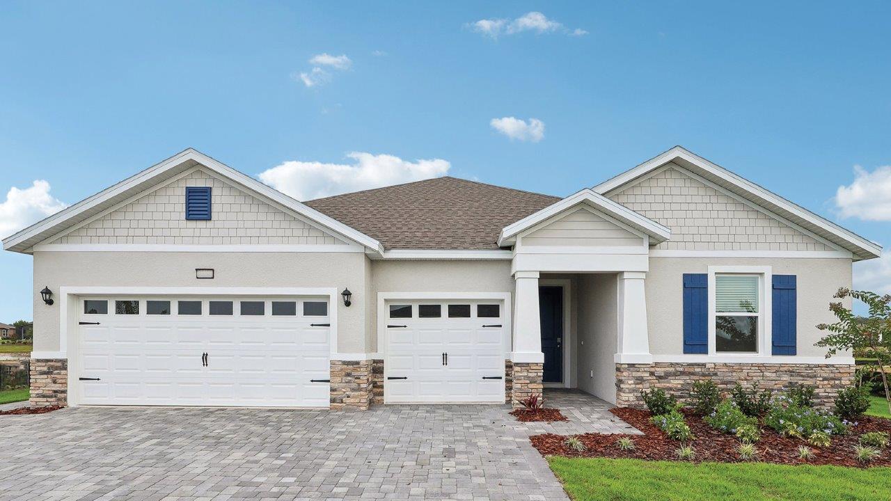 exterior image of a single-family home with stone accents, paver driveway, and three-car garage