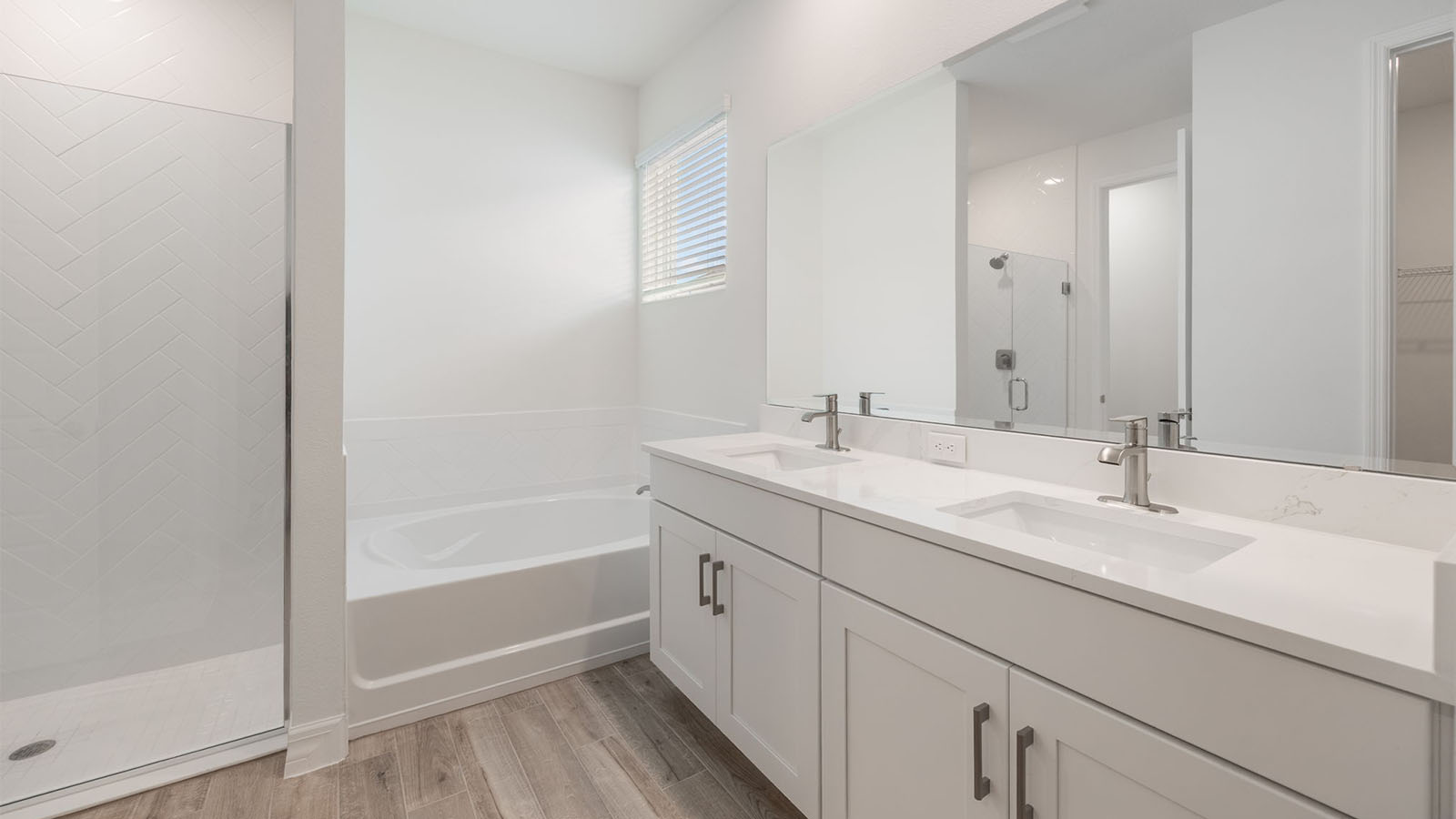 Primary bathroom with dual vanity sink, walk in shower, and garden tub