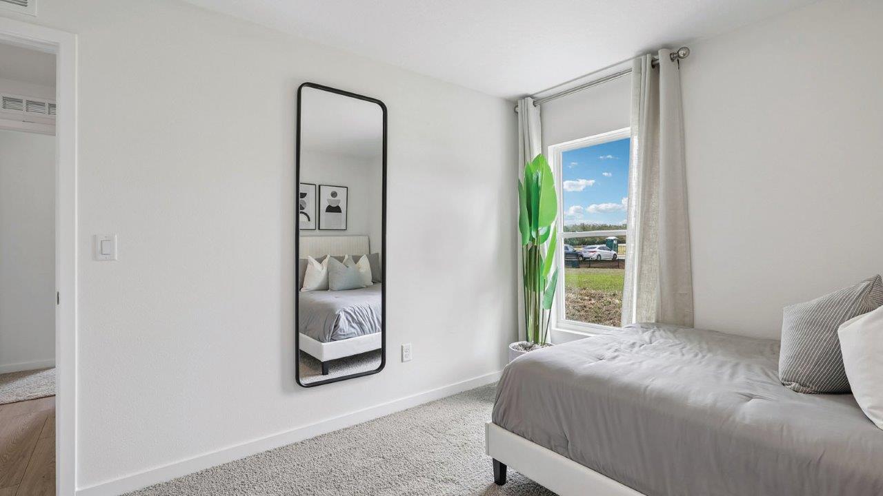 Guest room with full size bed and mirror near the window