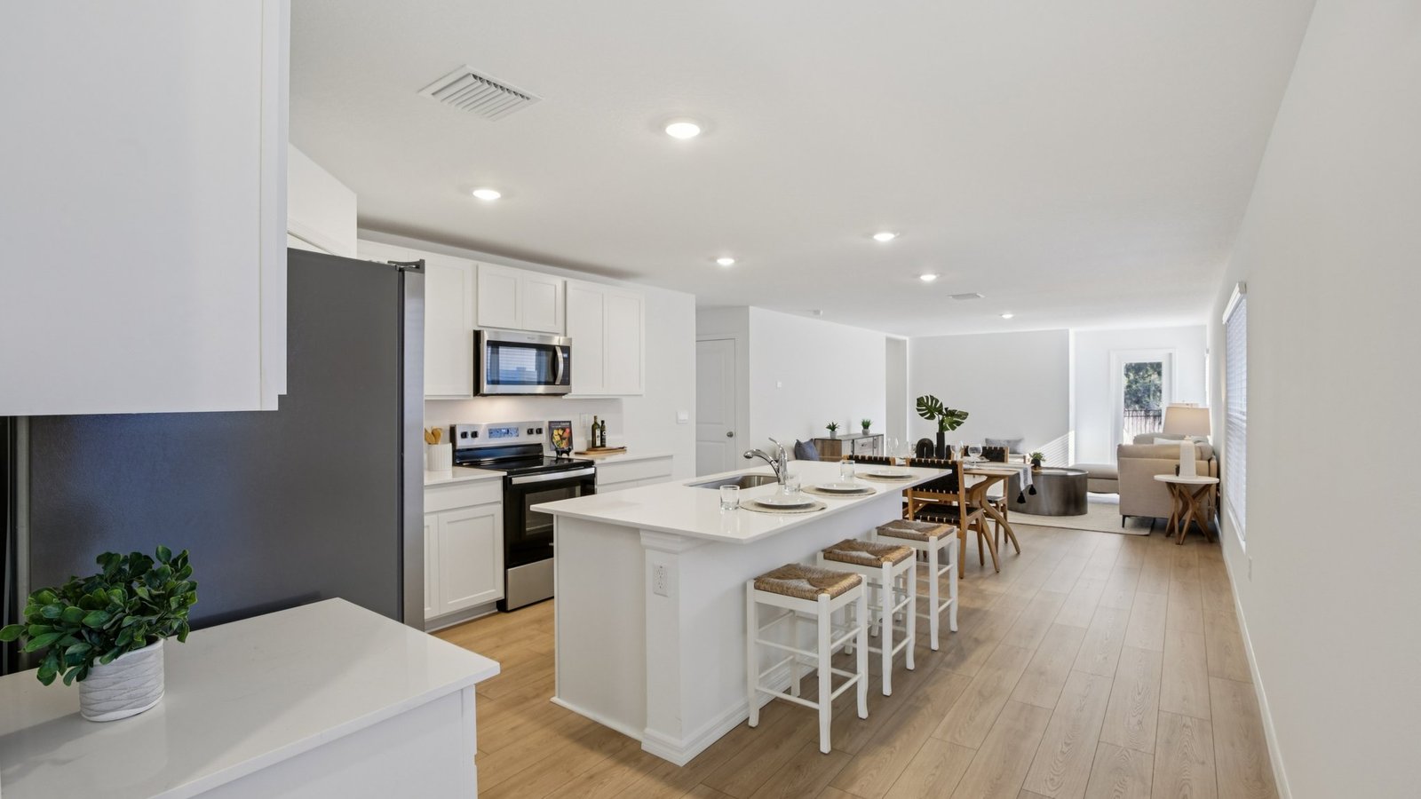 Kitchen with island seating, quartz counters, spacious pantry and stainless-steel appliances.