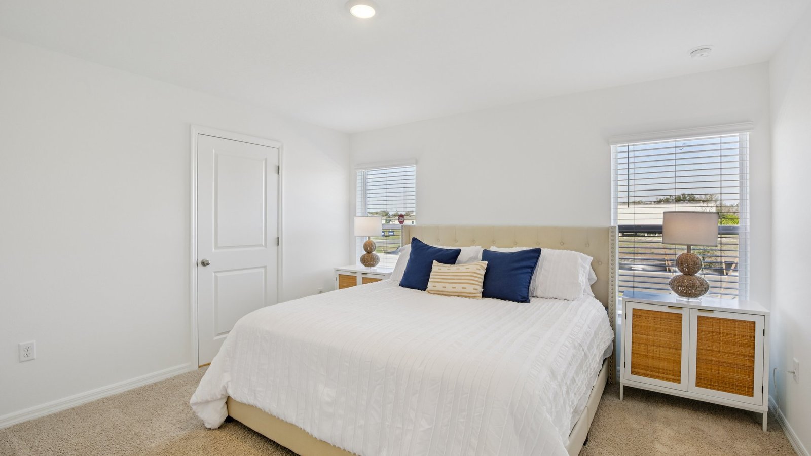Spacious primary bedroom with king size bed, carpet flooring, natural lighting and a walk in closet.