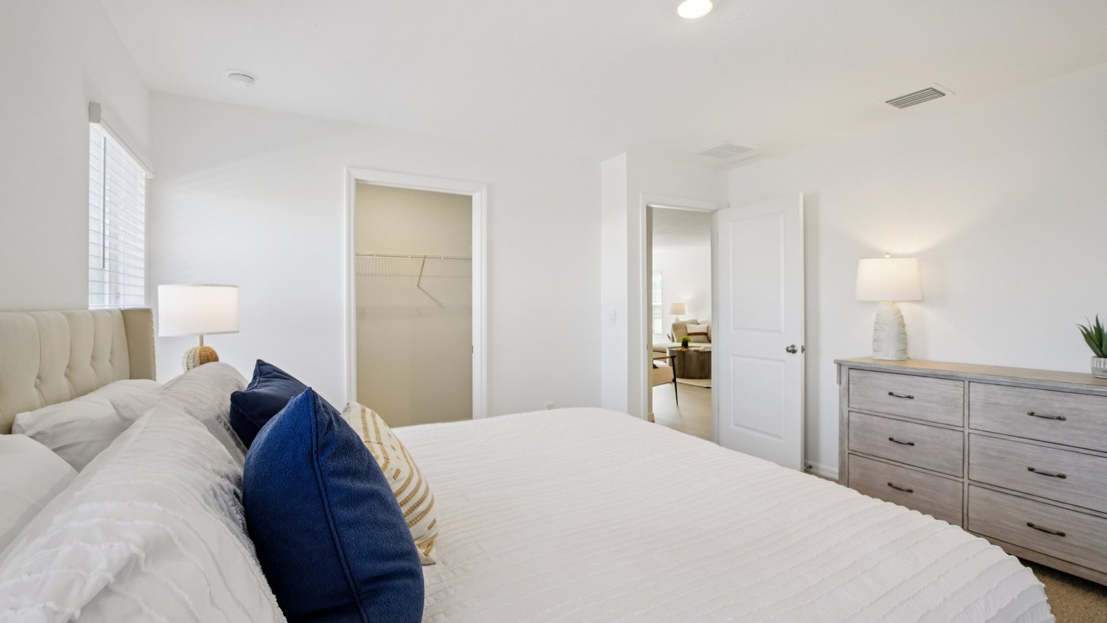 Spacious primary bedroom with king size bed, carpet flooring, natural lighting and a walk in closet.