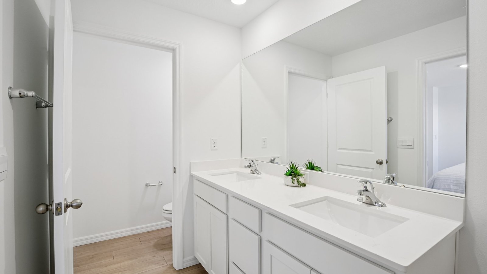 Modern bathroom with double vanity sinks, large wall mirror, cabinets and quartz countertops.