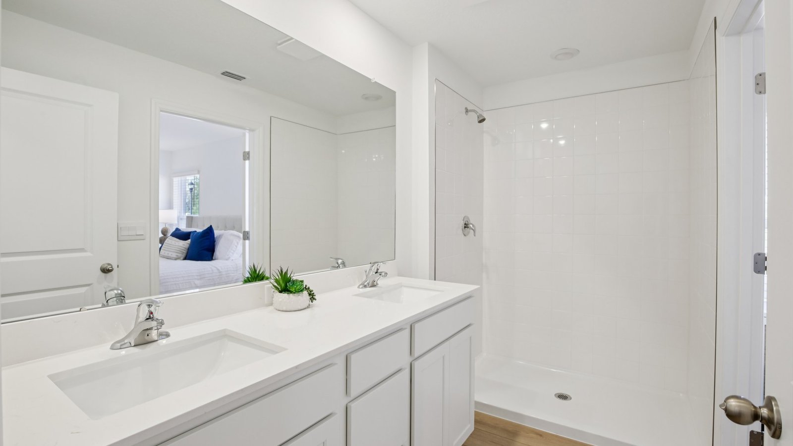 Modern bathroom with double vanity sinks, large wall mirror, cabinets and quartz countertops.