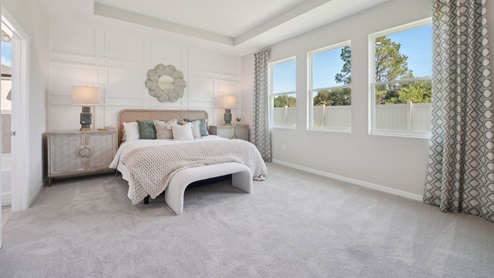 Spacious primary bedroom with king size bed, carpet flooring, natural lighting and a walk in closet.