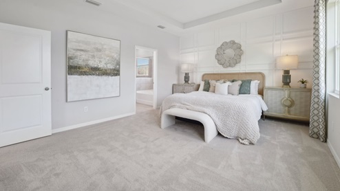 Spacious primary bedroom with king size bed, carpet flooring, natural lighting and a walk in closet.