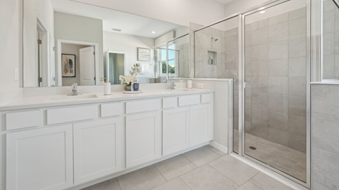 Modern bathroom with double vanity sinks, large wall mirror, cabinets and quartz countertops.