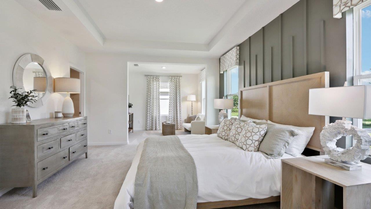 Spacious primary bedroom with king size bed, carpet flooring, natural lighting and a walk-in closet.