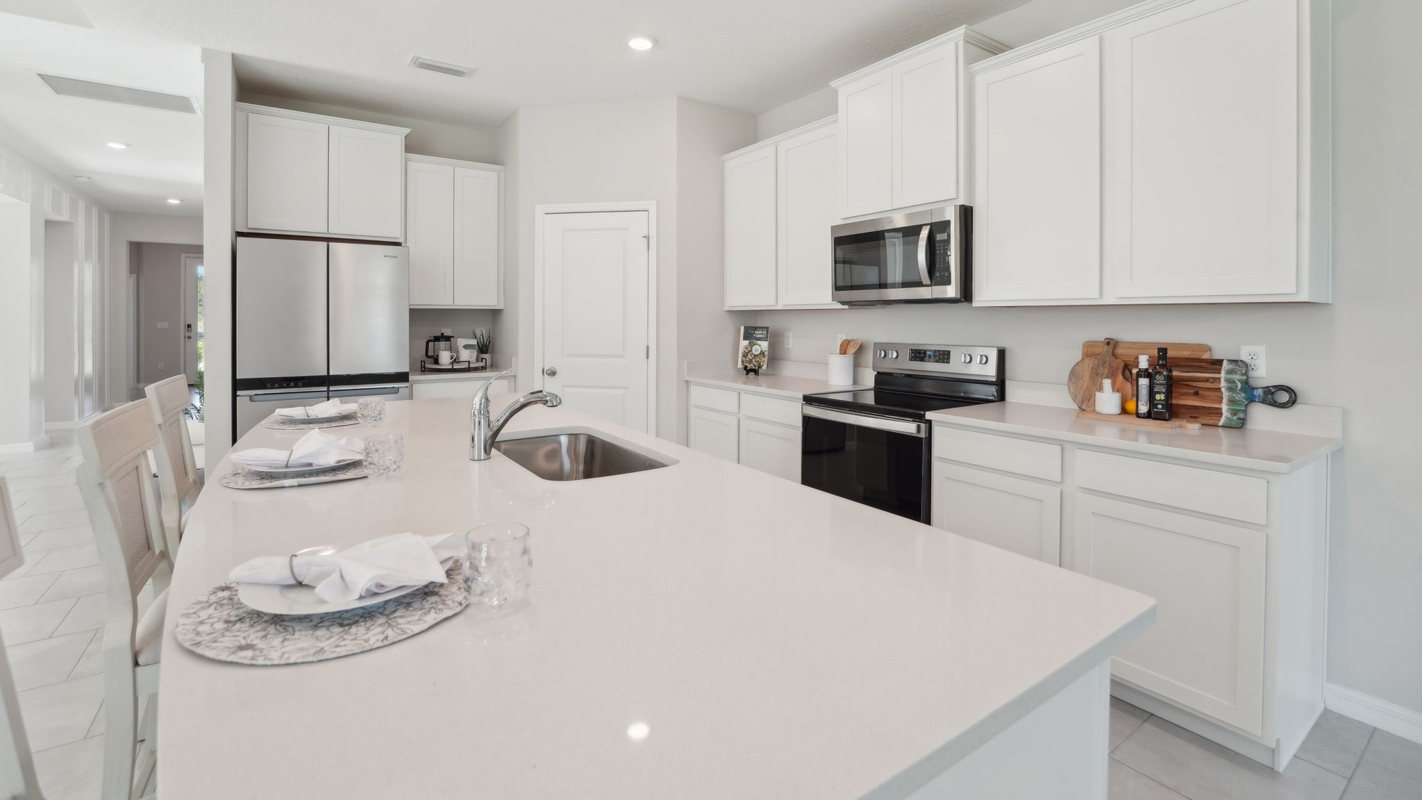 Kitchen with island seating, quartz counters, spacious pantry and stainless-steel appliances.