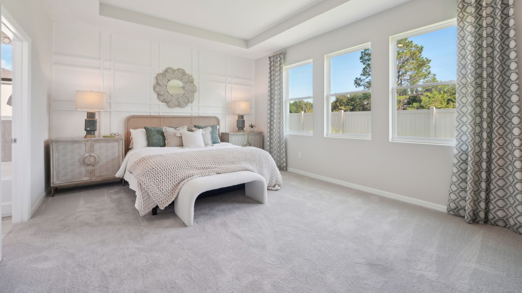 Spacious primary bedroom with king size bed, carpet flooring, natural lighting and a walk-in closet.