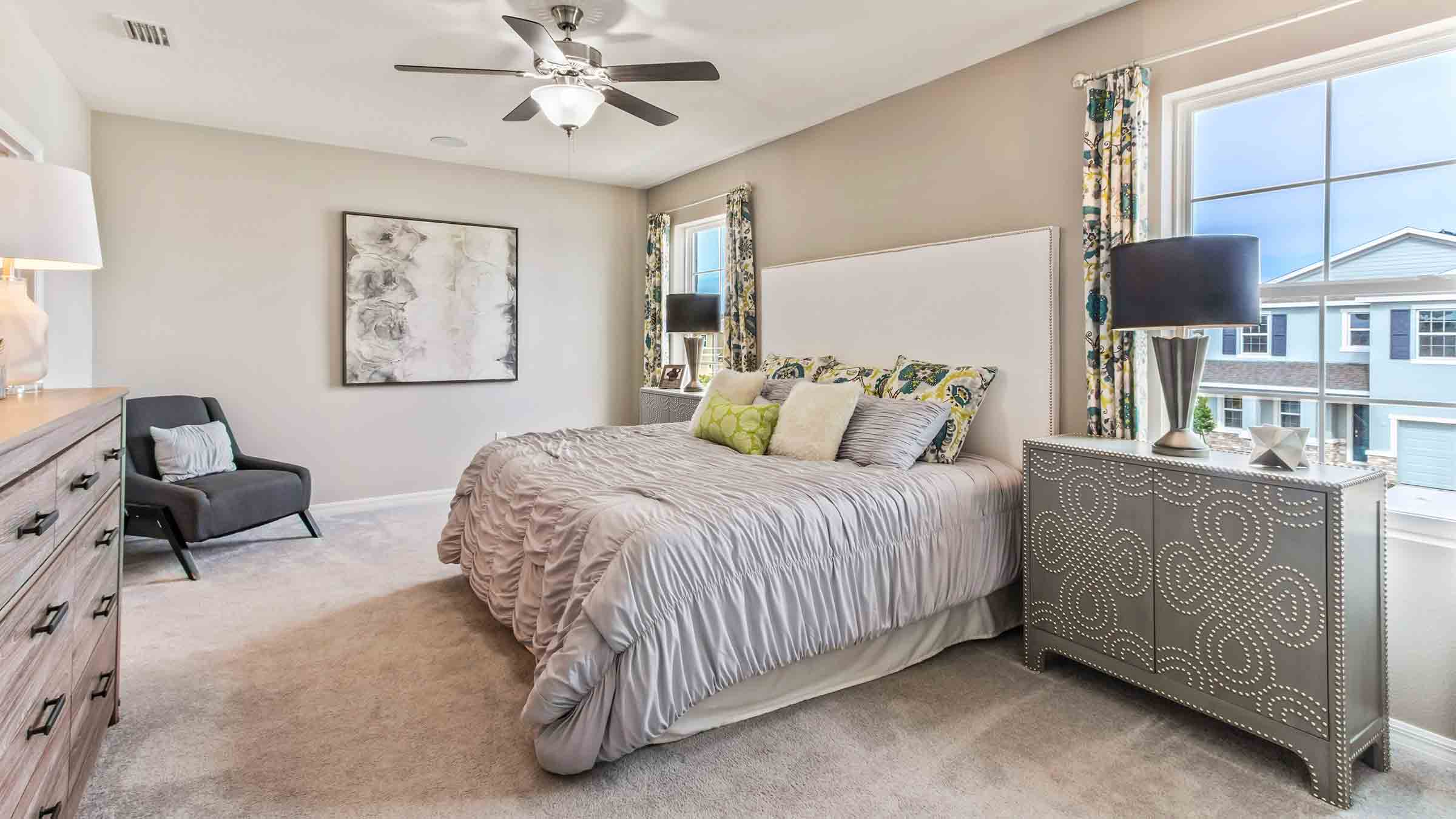 Spacious primary bedroom with king size bed, carpet flooring, natural lighting and a walk-in closet.