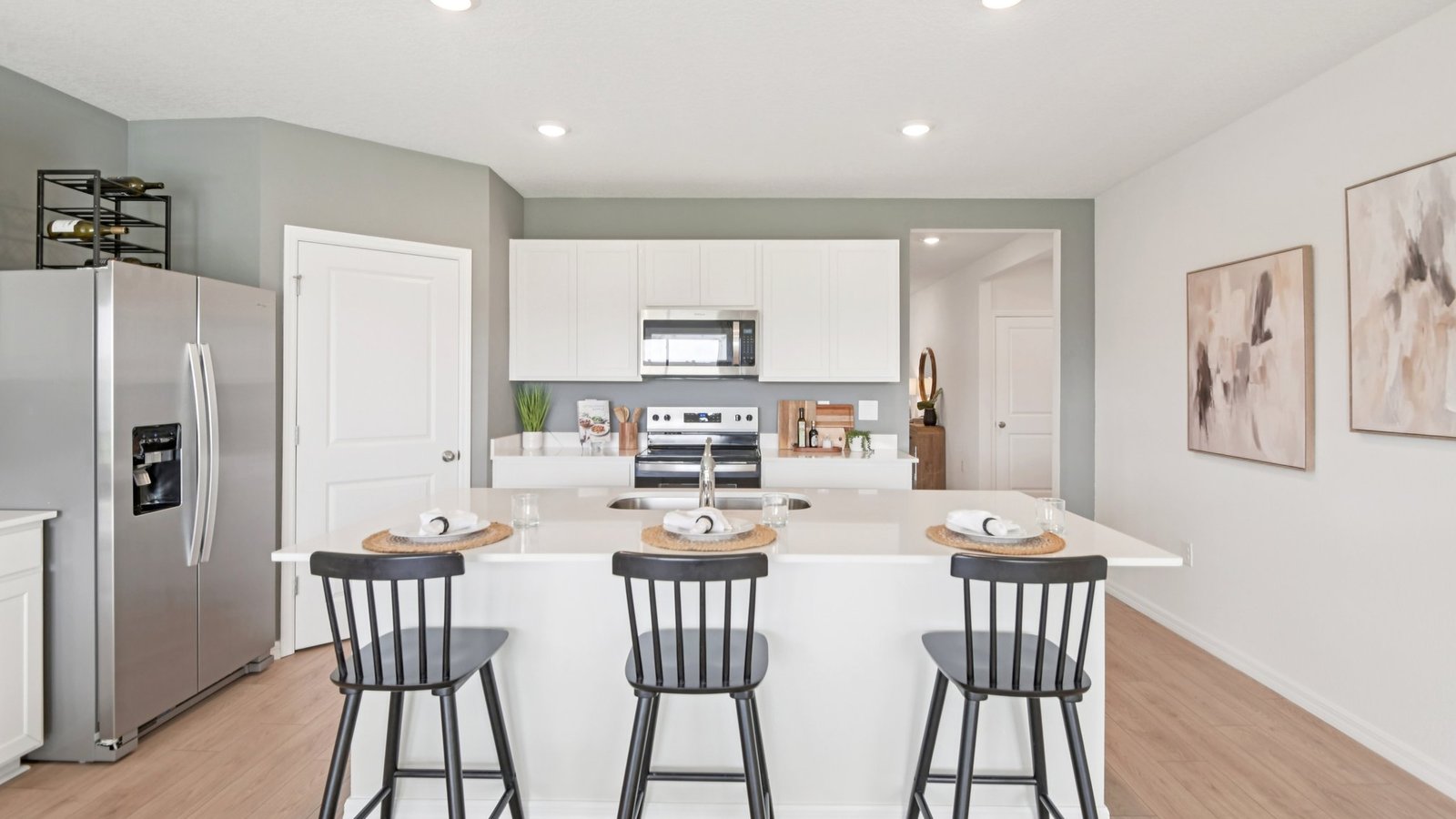 Kitchen with island seating, quartz counters, spacious pantry and stainless-steel appliances.