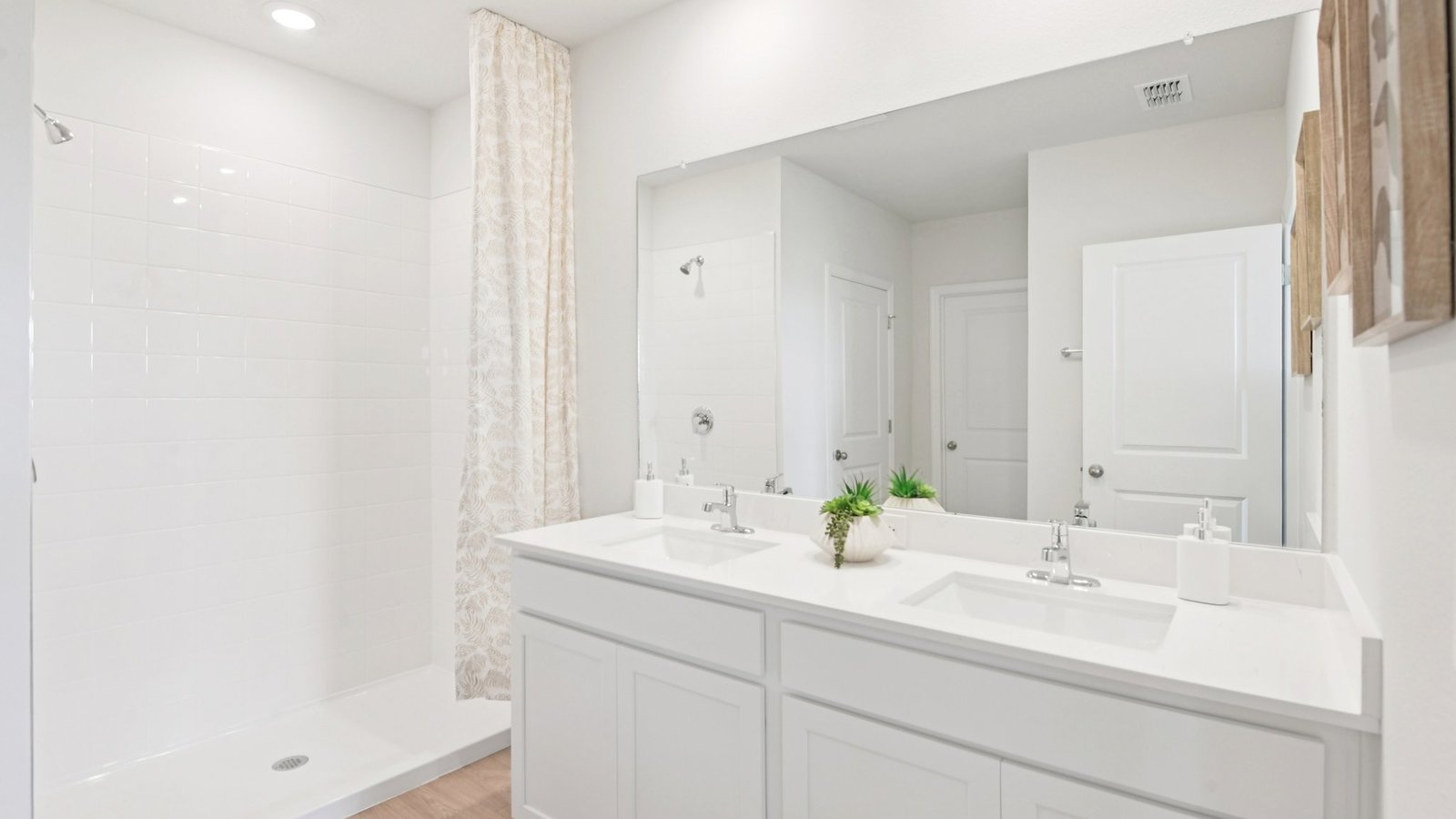 Modern bathroom with double vanity sinks, large wall mirror, cabinets and quartz countertops.