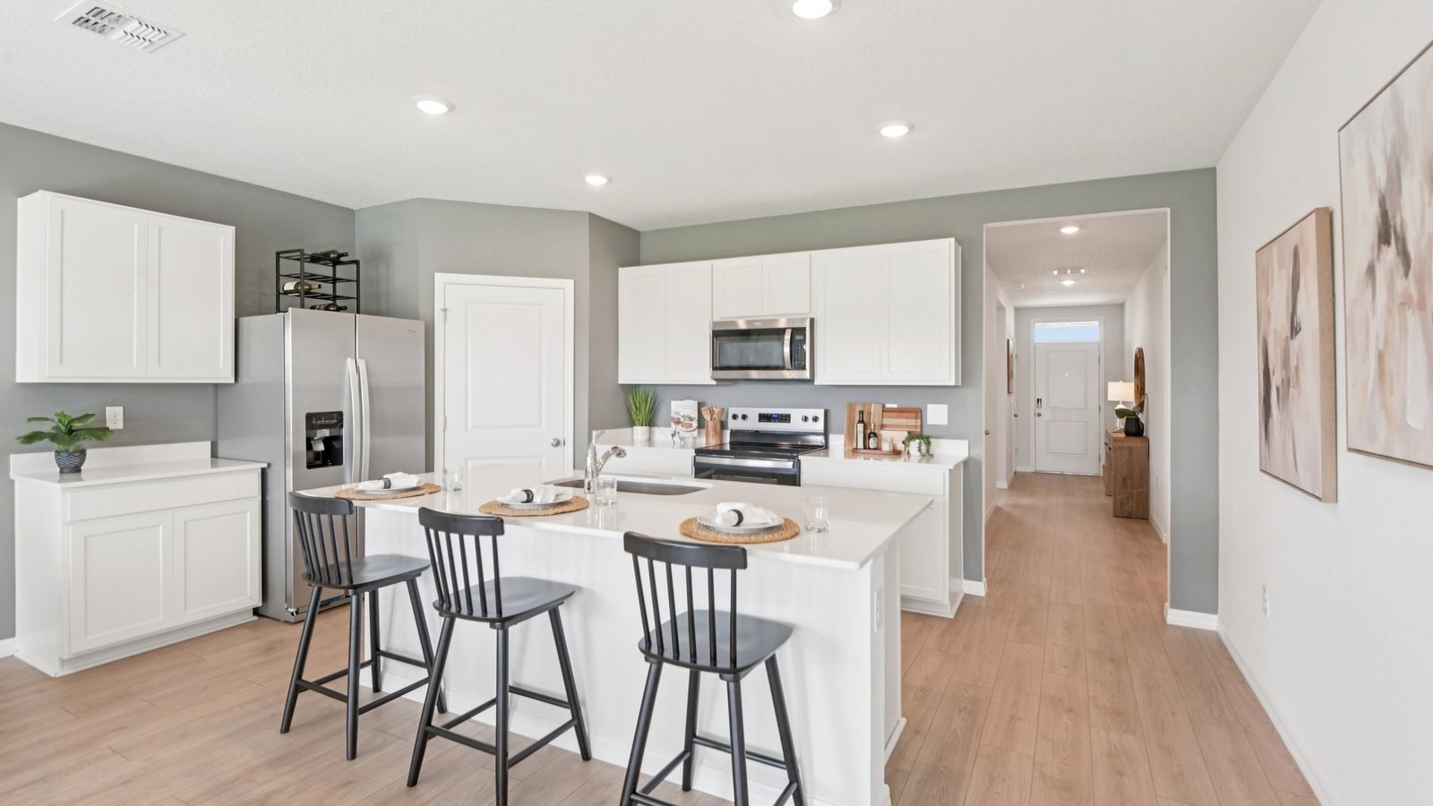Kitchen with island seating, quartz counters, spacious pantry and stainless-steel appliances.