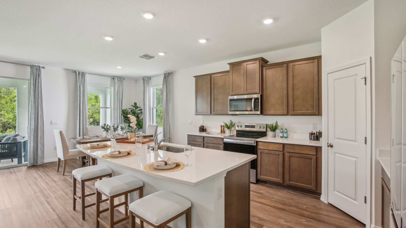 Kitchen with island seating, quartz counters, spacious pantry and stainless-steel appliances.