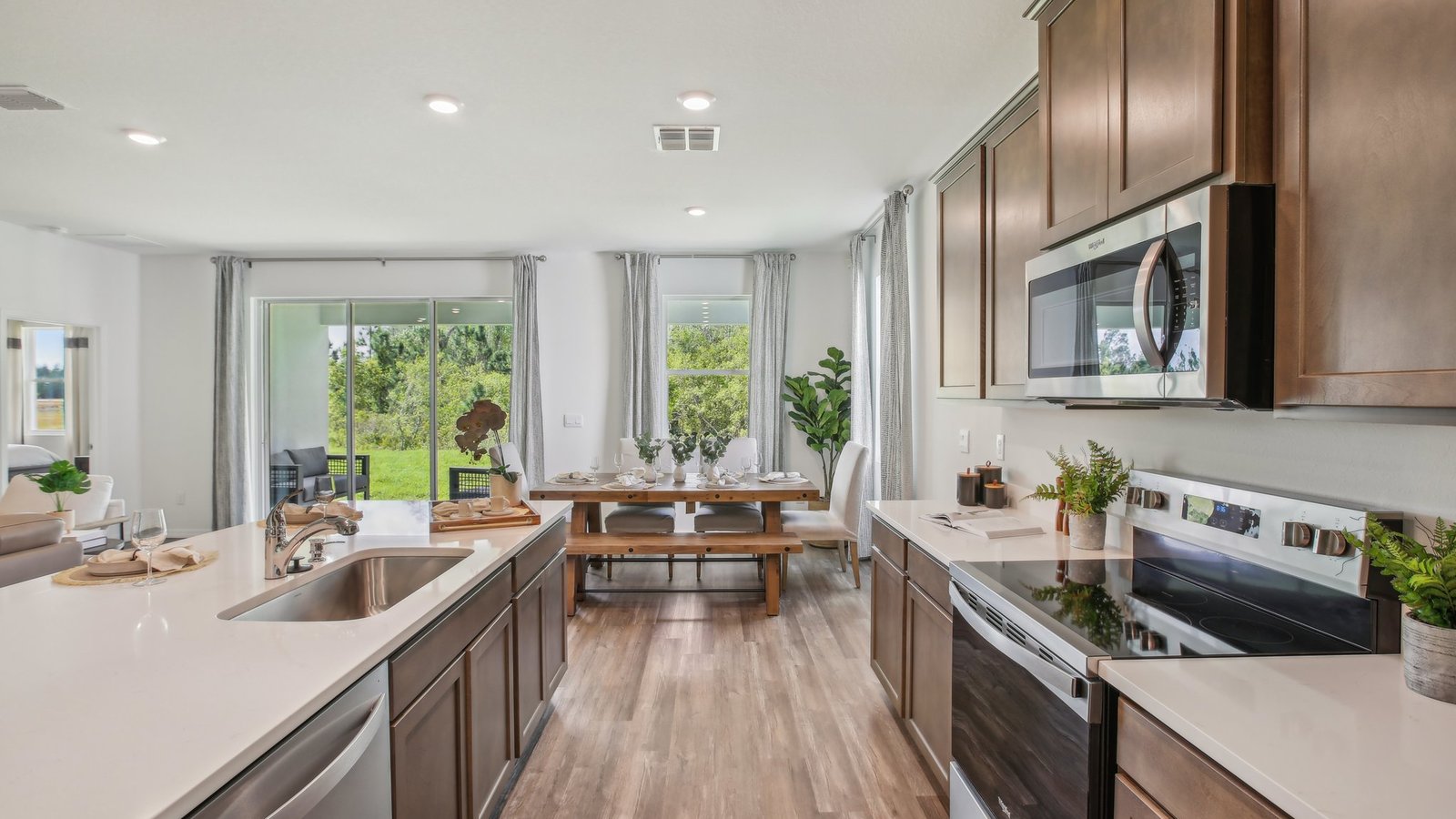 Kitchen with island seating, quartz counters, spacious pantry and stainless-steel appliances.