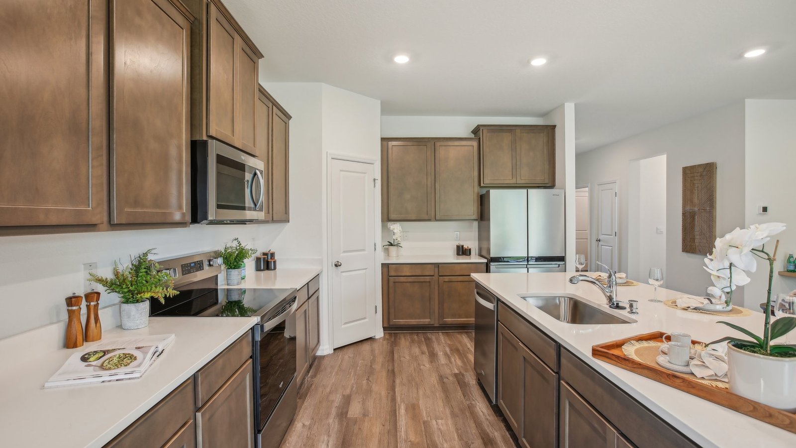 Kitchen with island seating, quartz counters, spacious pantry and stainless-steel appliances.