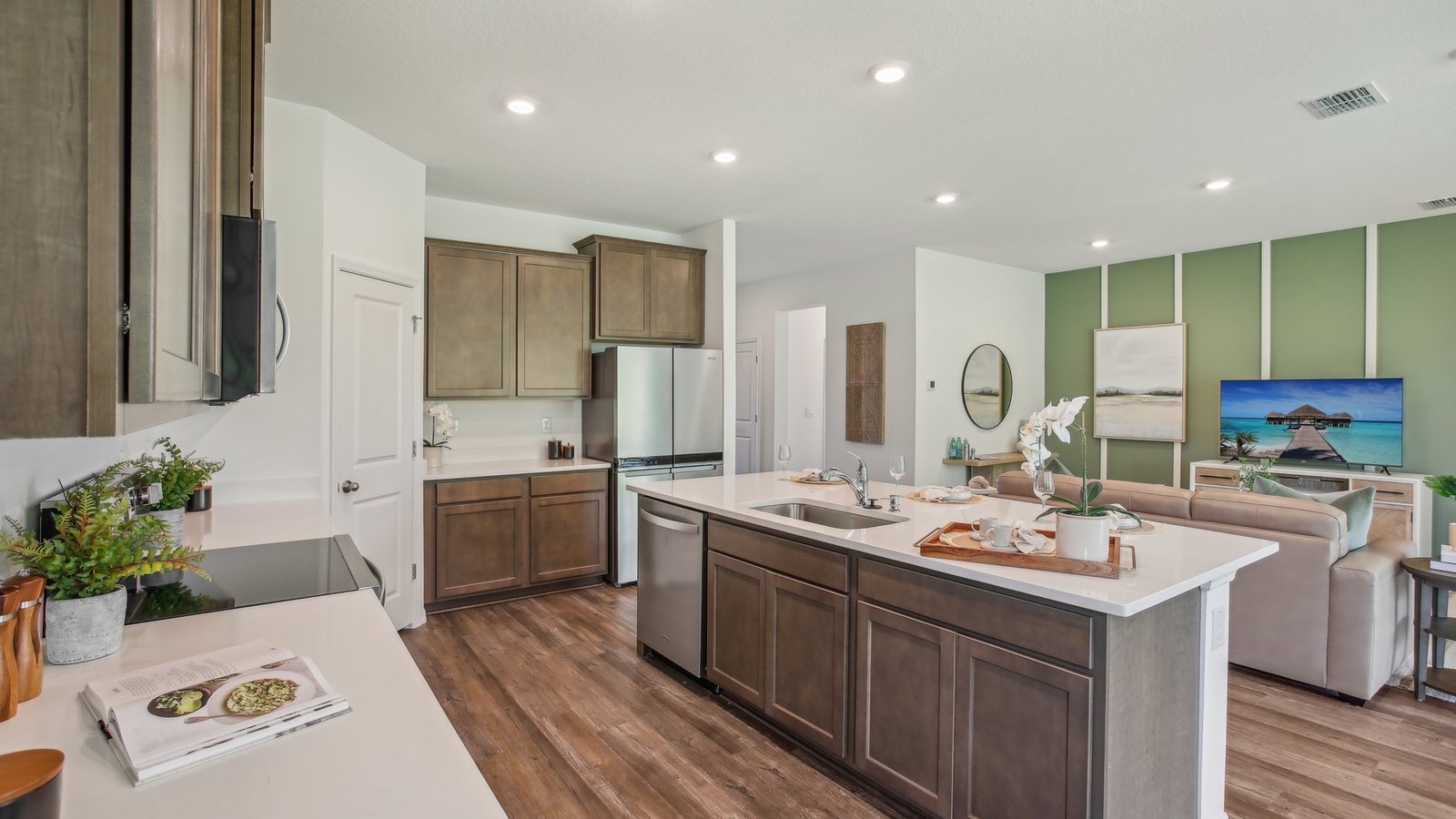 Kitchen with island seating, quartz counters, spacious pantry and stainless-steel appliances.
