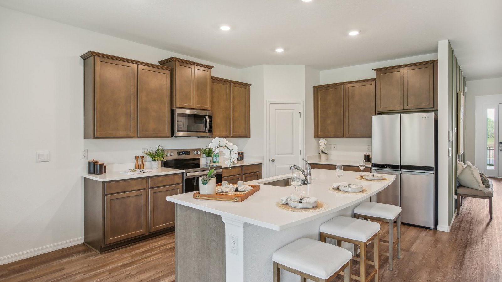 Kitchen with island seating, quartz counters, spacious pantry and stainless-steel appliances.