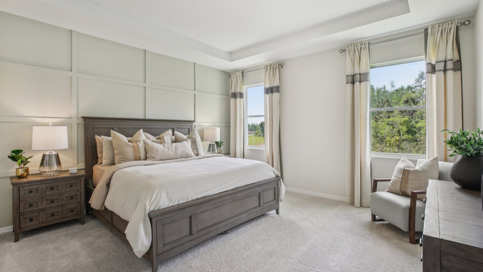 Spacious primary bedroom with king size bed, carpet flooring, natural lighting and a walk-in closet.