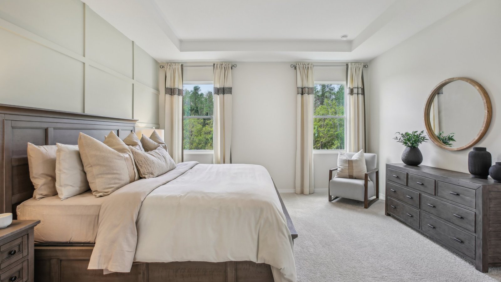 Spacious primary bedroom with king size bed, carpet flooring, natural lighting and a walk-in closet.