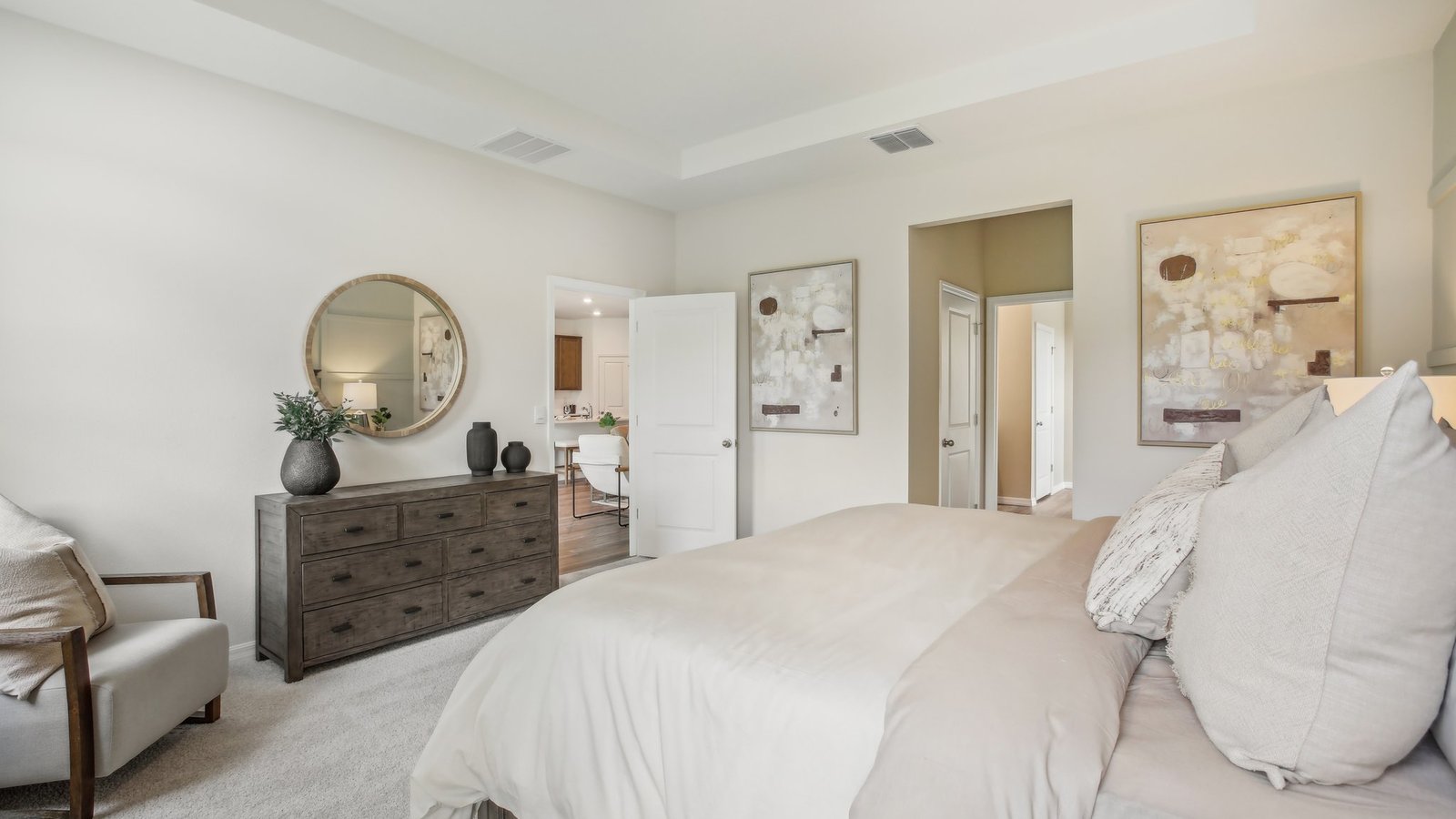 Spacious primary bedroom with king size bed, carpet flooring, natural lighting and a walk-in closet.