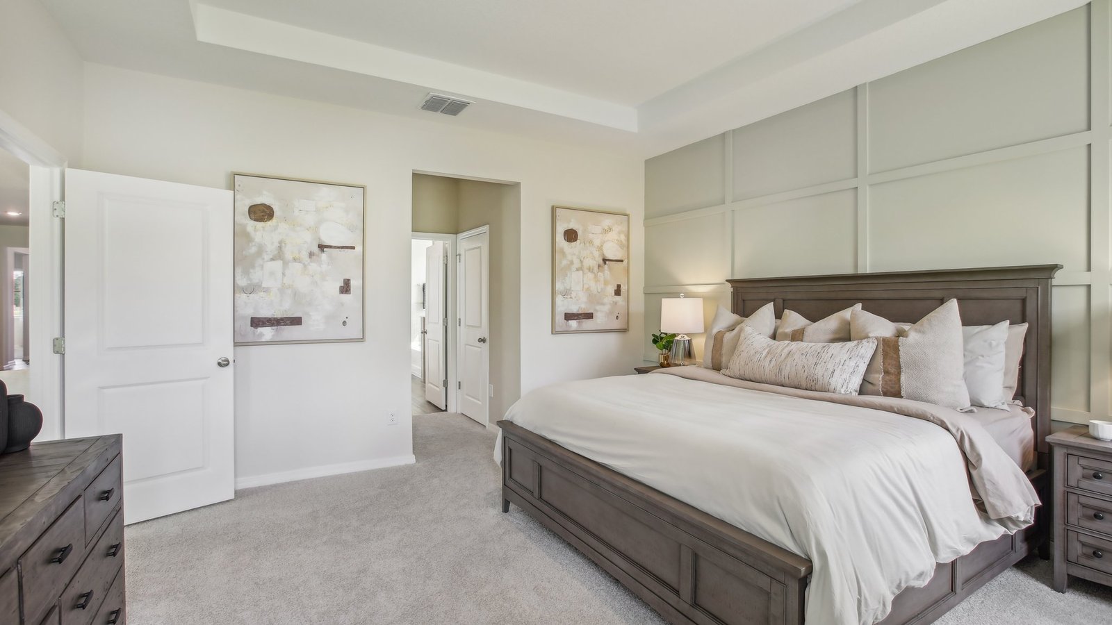 Spacious primary bedroom with king size bed, carpet flooring, natural lighting and a walk-in closet.