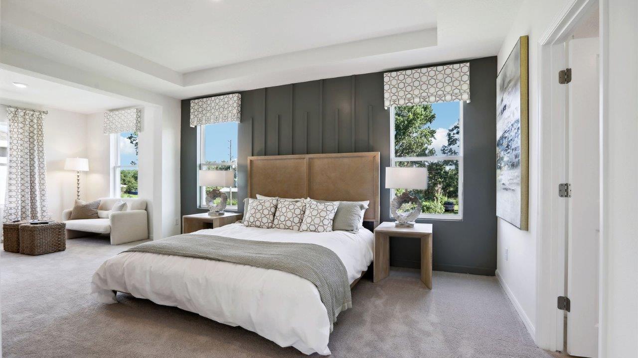 Spacious primary bedroom with king size bed, carpet flooring, natural lighting and a walk-in close