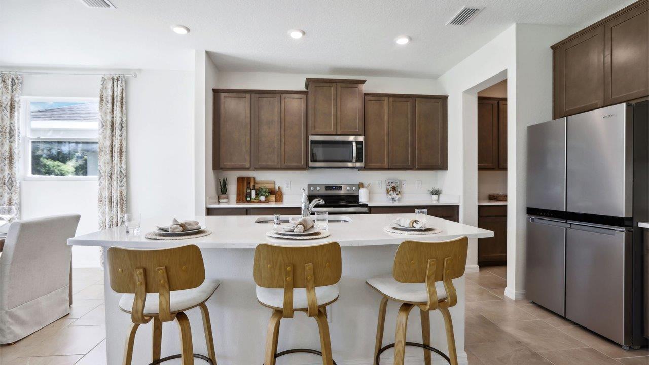 Kitchen with island seating, quartz counters, spacious pantry and stainless-steel appliances.