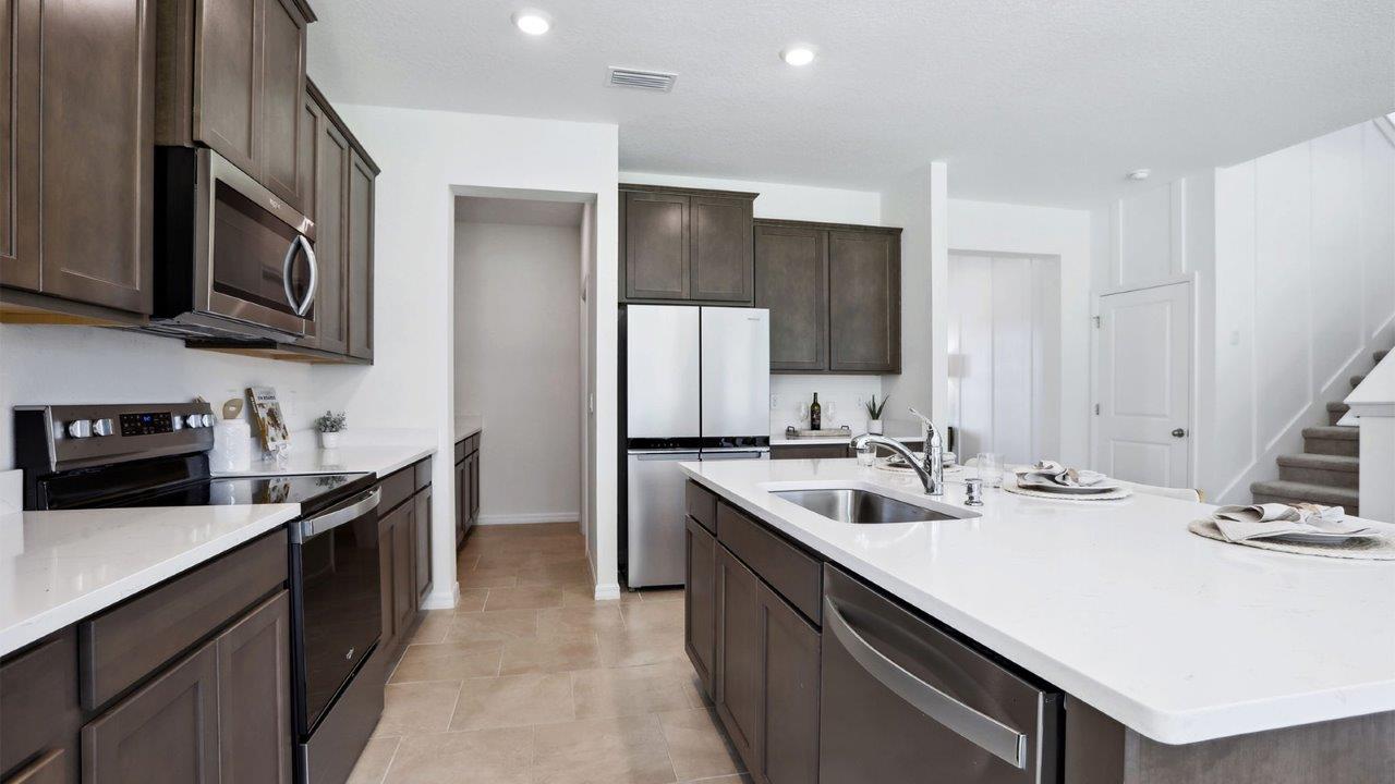 Kitchen with island seating, quartz counters, spacious pantry and stainless-steel appliances.