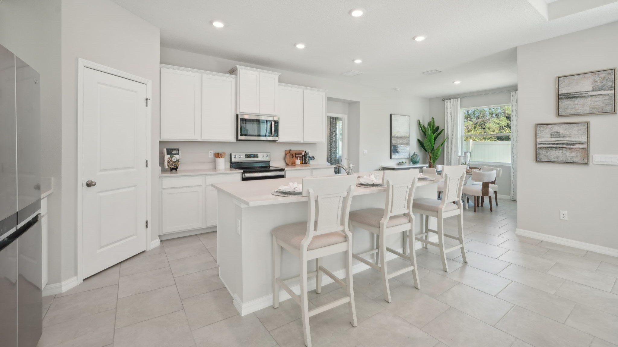 Kitchen with island seating, quartz counters, spacious pantry and stainless-steel appliances.