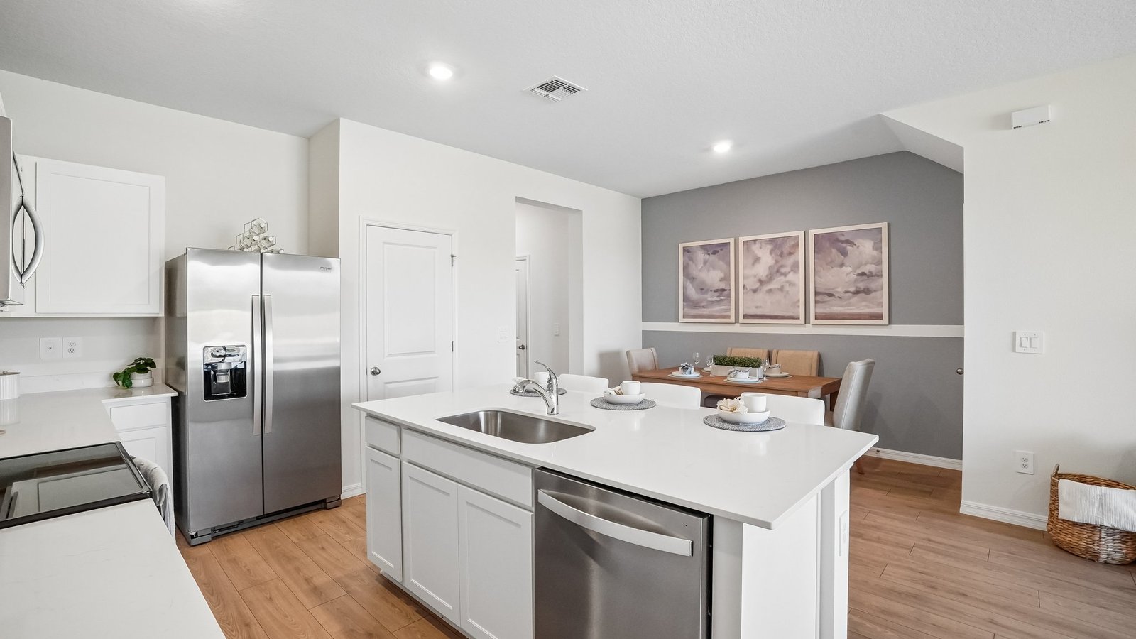 Kitchen with island seating, quartz counters, spacious pantry and stainless-steel appliances.