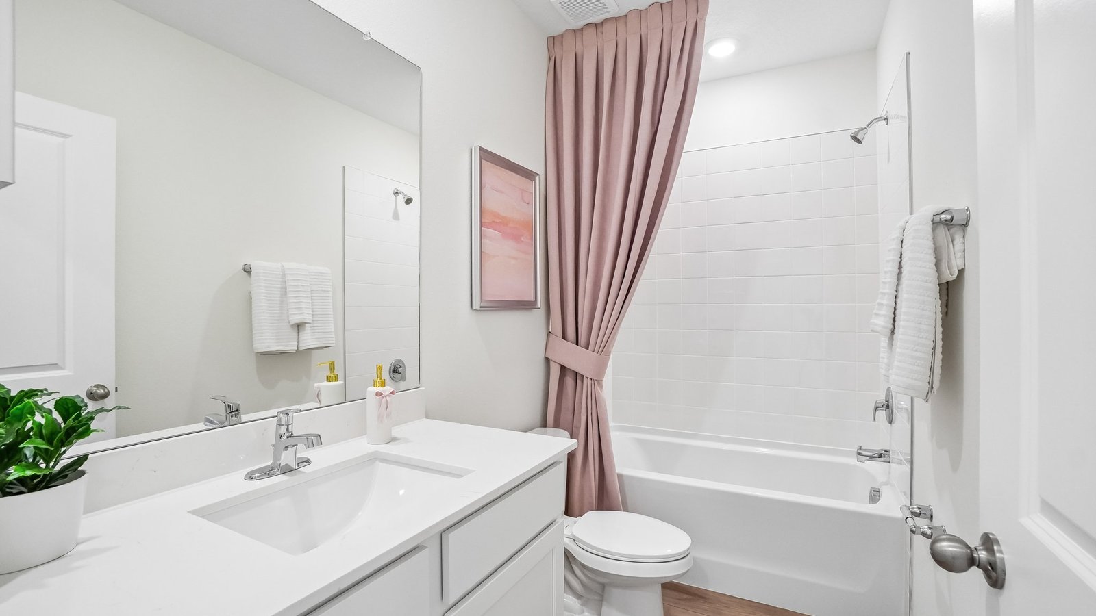 Modern bathroom with single bowl sink, quartz vanity, wall mirror, cabinets and toilet.