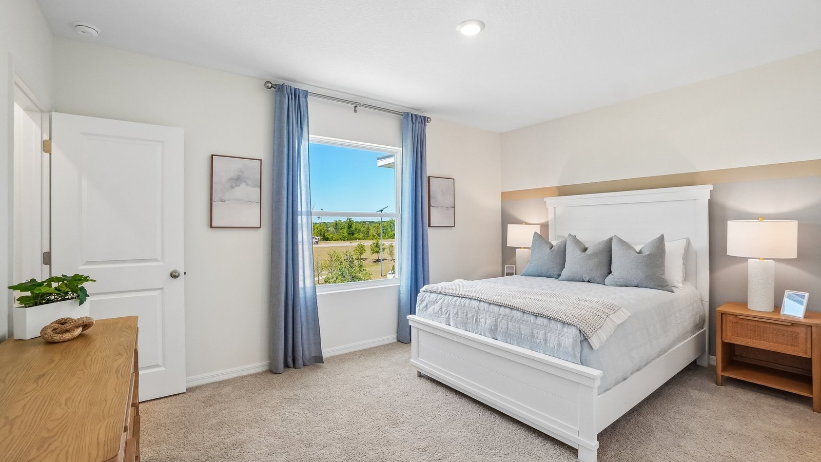 Spacious primary bedroom with king size bed, carpet flooring, natural lighting and a walk in closet.