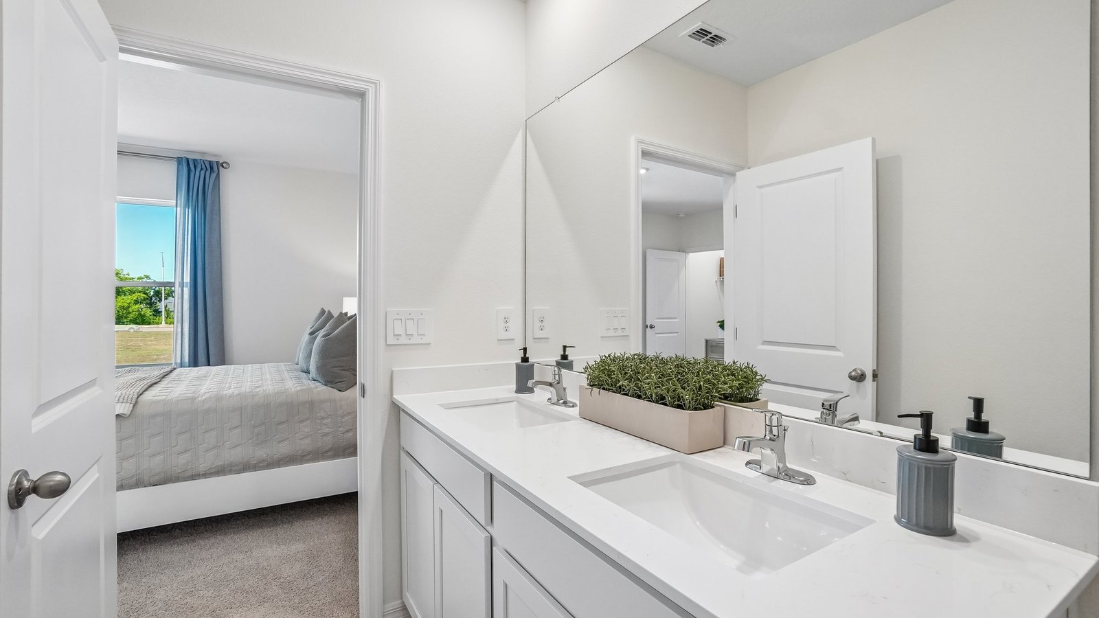 Modern bathroom with double vanity sinks, large wall mirror, cabinets and quartz countertops.