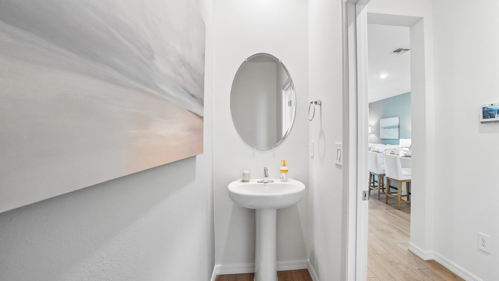 Modern bathroom with single bowl sink, quartz vanity, wall mirror, cabinets and toilet.
