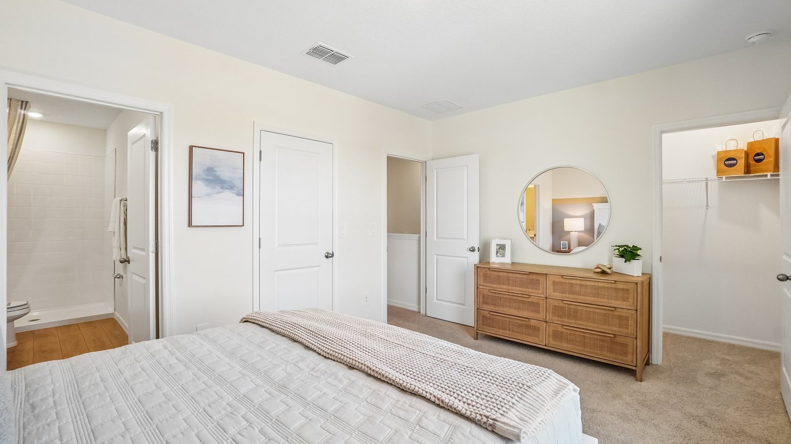 Spacious primary bedroom with king size bed, carpet flooring, natural lighting and a walk in closet.