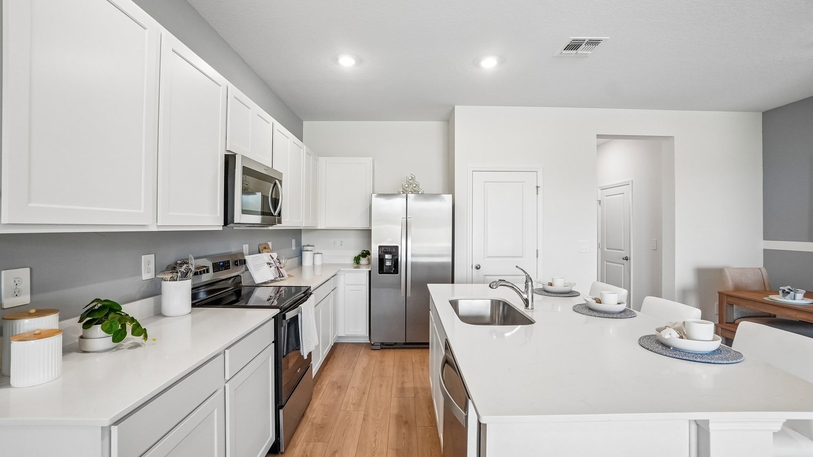 Kitchen with island seating, quartz counters, spacious pantry and stainless-steel appliances.