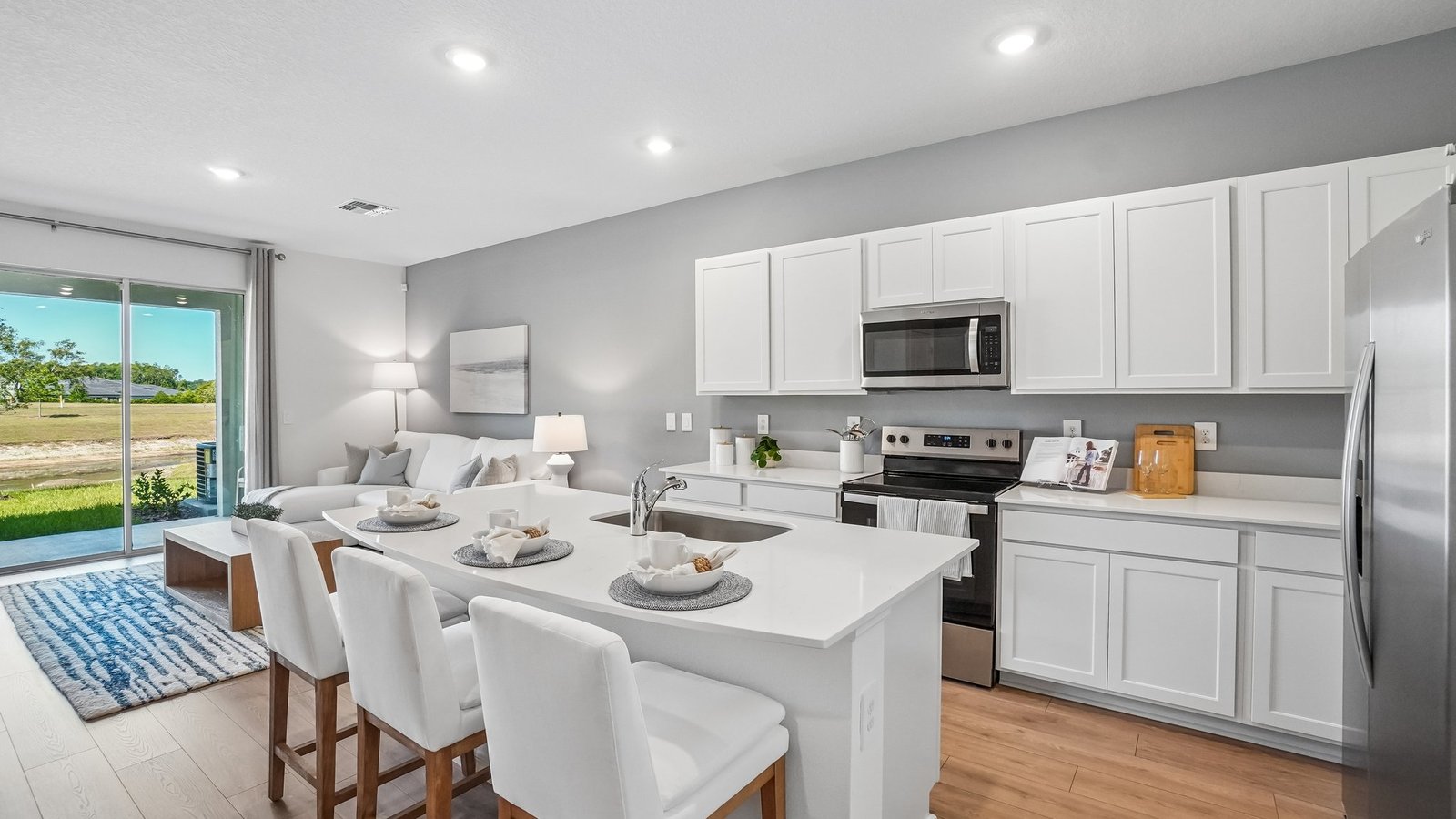 Kitchen with island seating, quartz counters, spacious pantry and stainless-steel appliances.