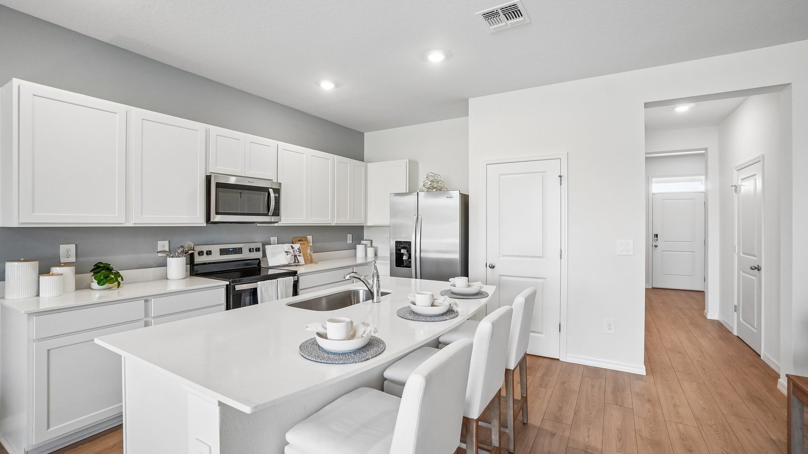 Kitchen with island seating, quartz counters, spacious pantry and stainless-steel appliances.