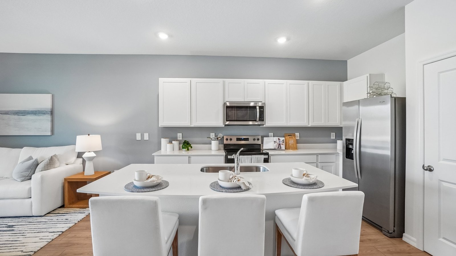 Kitchen with island seating, quartz counters, spacious pantry and stainless-steel appliances.