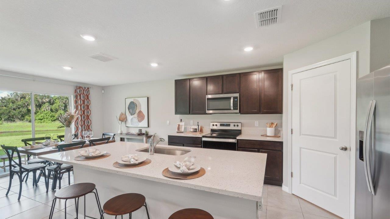 Kitchen with island seating, quartz counters, spacious pantry and stainless-steel appliances.