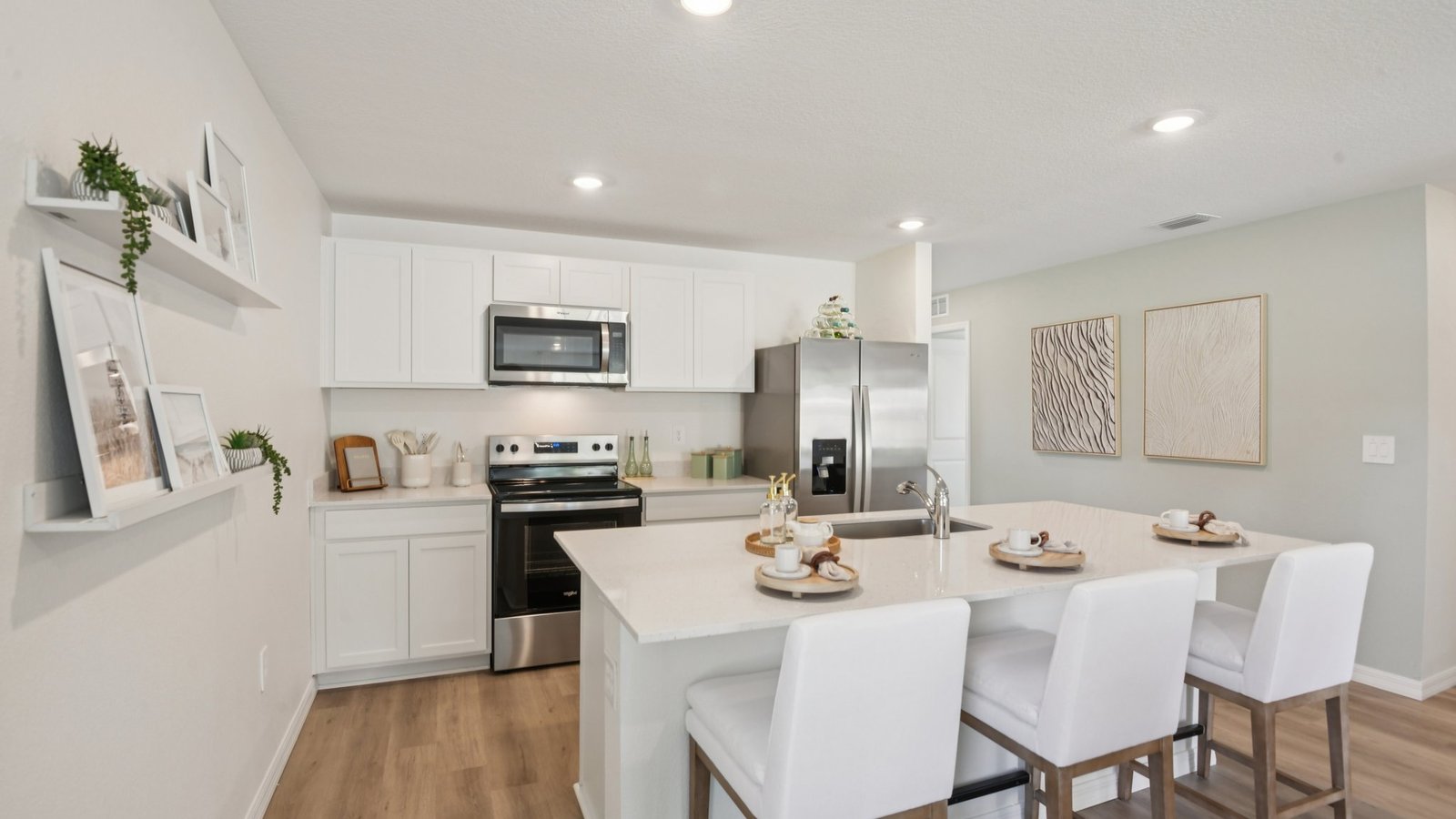 Kitchen with island seating, quartz counters, spacious pantry and stainless-steel appliances.