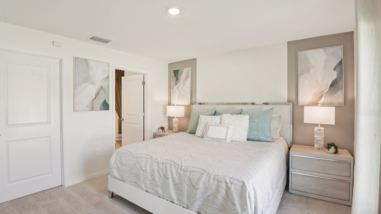 Spacious primary bedroom with king size bed, carpet flooring, natural lighting and a walk in closet.