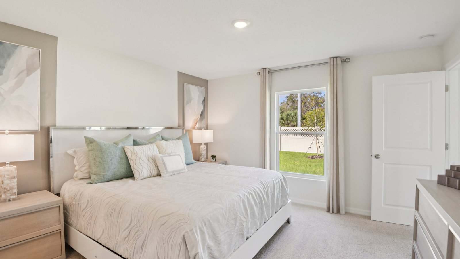 Spacious primary bedroom with king size bed, carpet flooring, natural lighting and a walk in closet.
