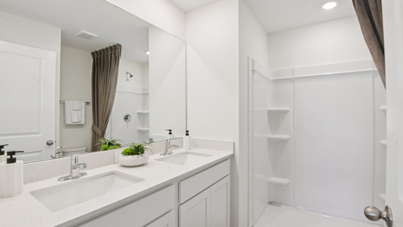 Modern bathroom with double vanity sinks, large wall mirror, cabinets and quartz countertops.