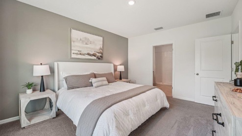 Spacious primary bedroom with king size bed, carpet flooring, natural lighting and a walk in closet.