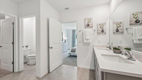 Modern bathroom with double vanity sinks, large wall mirror, cabinets and quartz countertops.