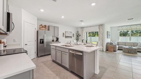 Kitchen with island seating, quartz counters, spacious pantry and stainless-steel appliances.